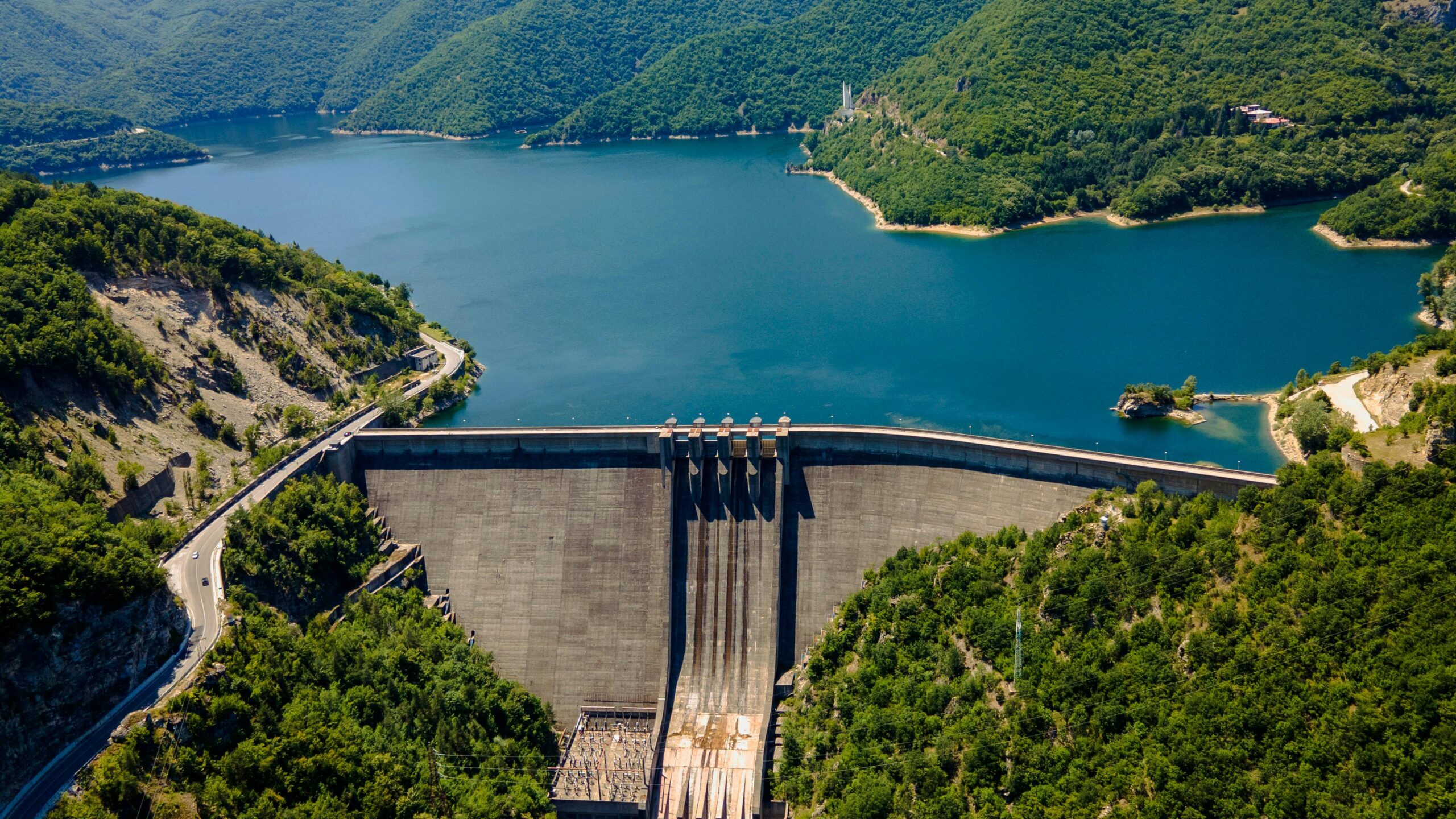 Scenic aerial shot of Vacha Reservoir surrounded by lush green forests and mountains in Bulgaria.