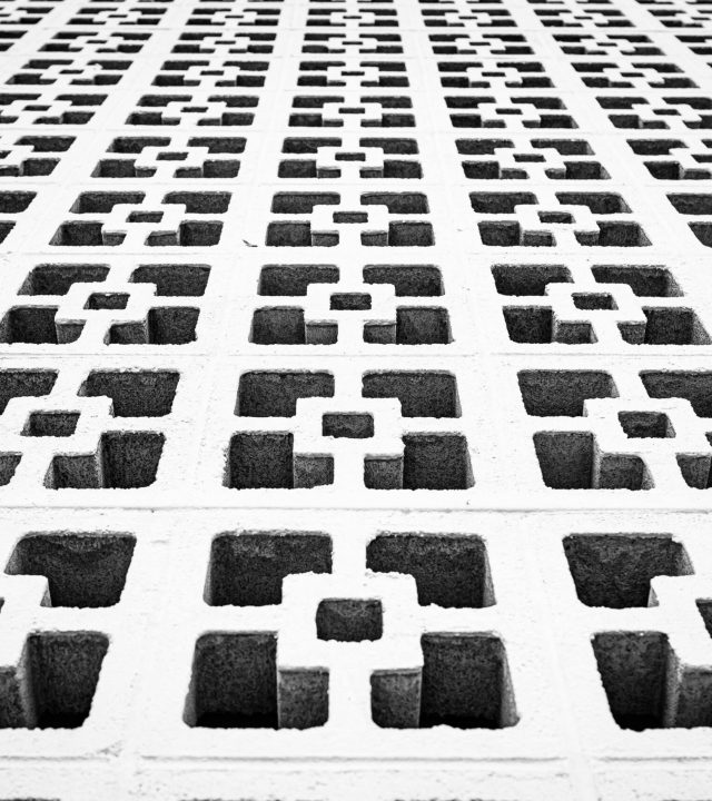 Black and white photo of a modern concrete wall with geometric patterns, showcasing symmetry and abstract design.
